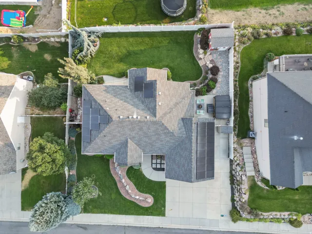 Pitched roofline with solar panels, mature landscaping, manicured lawn, stone pathway, and a detached shed