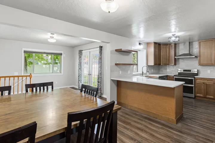 Modern kitchen featuring wood-finish flooring, light-toned countertops, and a gray tile backsplash