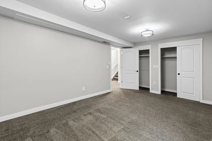 Spacious finished basement featuring neutral wall finishes, carpeted flooring, recessed ceiling lighting, and multiple closet storage with white panel doors