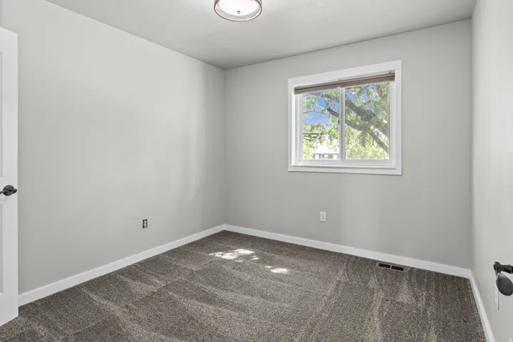 Neutral-toned walls, textured carpet flooring, and a white-framed window