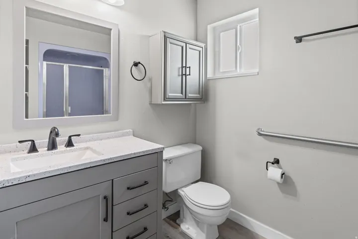 Vanity with integral sink and dark-finish faucet, framed mirror, wall-mounted medicine cabinet, toilet, and window