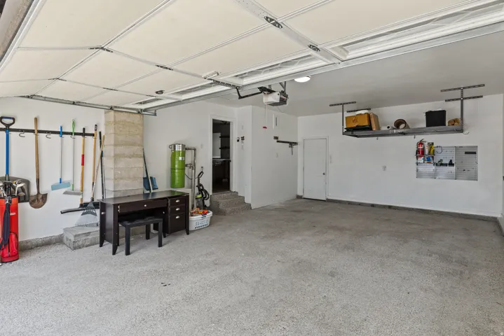 Two-car garage featuring an epoxy-coated floor, painted white walls, and an overhead storage rack
