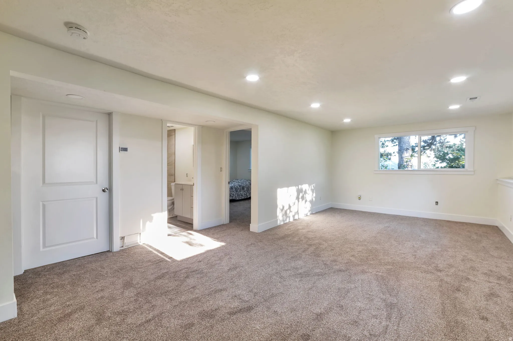 Recessed lighting, carpet flooring, interior window, white trim, and a white interior door