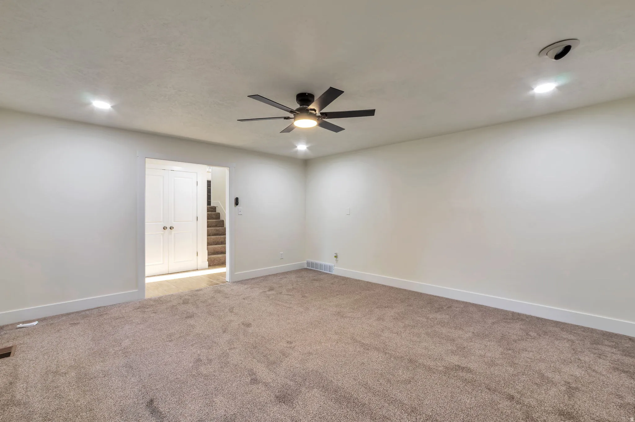 Recessed lighting, ceiling fan with integrated light, light-toned carpeting, white walls, and white trim
