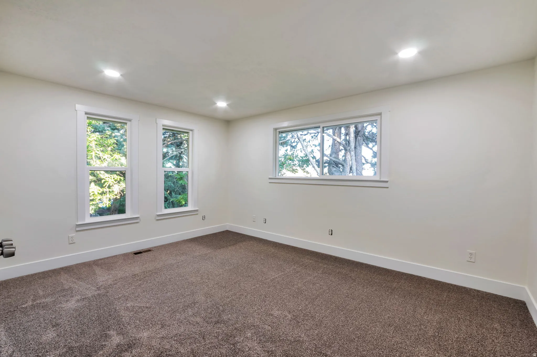 Recessed lighting with light-colored walls, multiple windows, and plush carpeting