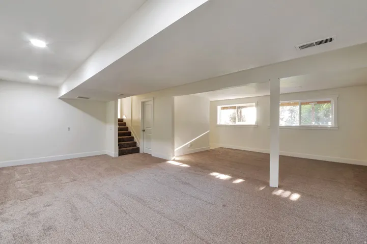 Spacious room featuring neutral carpeting, recessed lighting, and multiple windows
