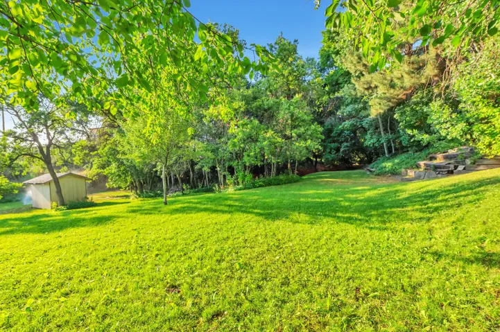 Expansive manicured lawn with mature shade trees and natural landscape borders, offering abundant outdoor space and verdant grounds ideal for recreation and entertaining