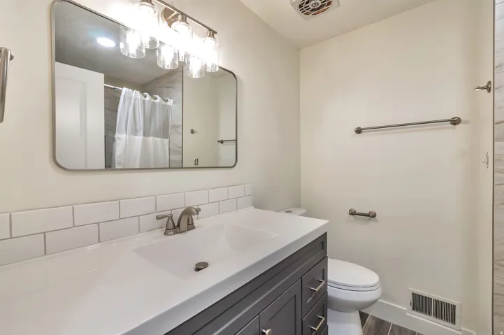Vanity with a built-in rectangular sink, white countertop, dark wood-finish cabinetry, and brushed nickel hardware