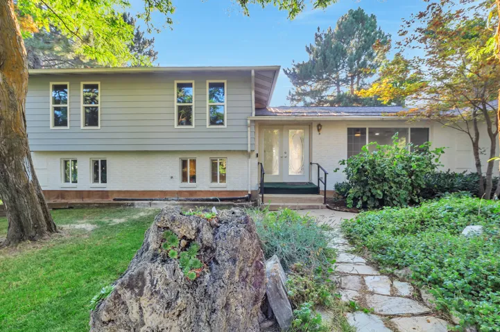 Dual pane windows, white brick lower exterior, light gray siding upper exterior, stone pathway, mature landscaping
