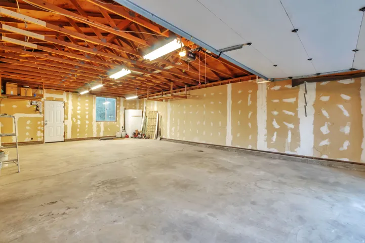 Spacious open floor plan with exposed wood-beam ceiling, polished concrete flooring, and abundant natural light from large window openings