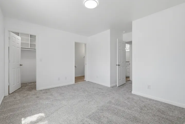 Spacious room featuring light gray carpeting, white walls, and bright overhead lighting