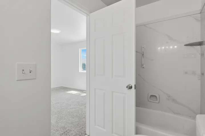 Bathroom featuring a white bathtub with a tile surround and a visible shower head