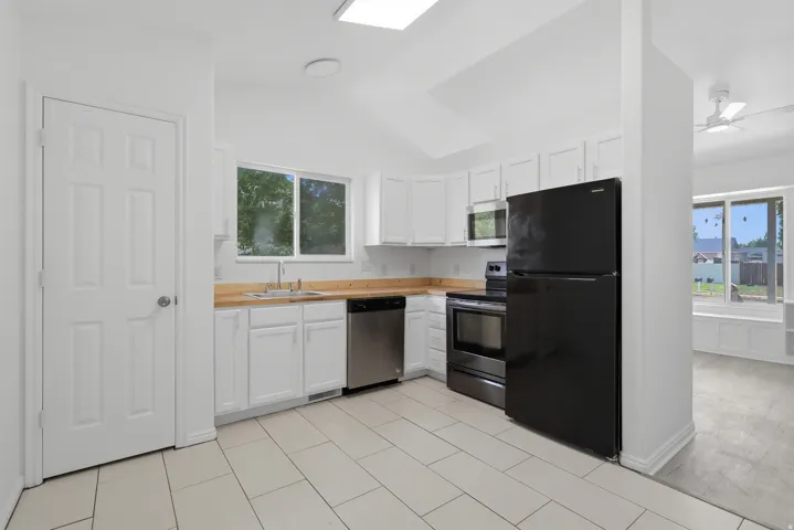 Kitchen featuring white cabinetry, light wood-finish countertops, and white tile flooring