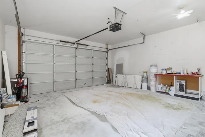 Attached garage featuring a white paneled door, concrete flooring, and ceiling-mounted garage door opener