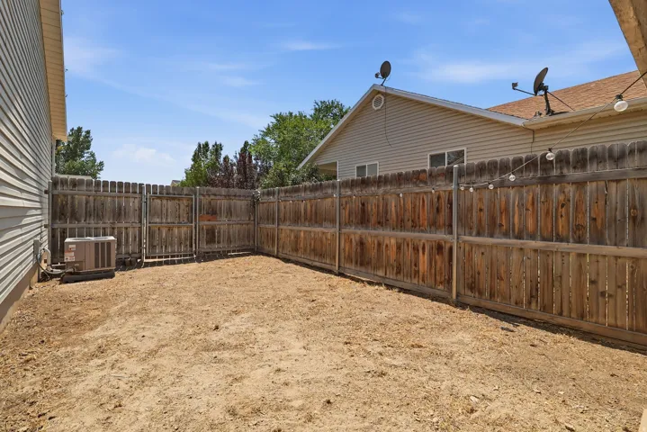 Fenced backyard with bare earth landscaping, featuring a wooden privacy fence and a side gate