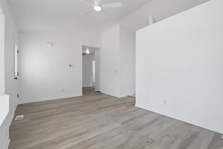 Spacious living area featuring wood-finish flooring, vaulted ceilings, and a ceiling fan