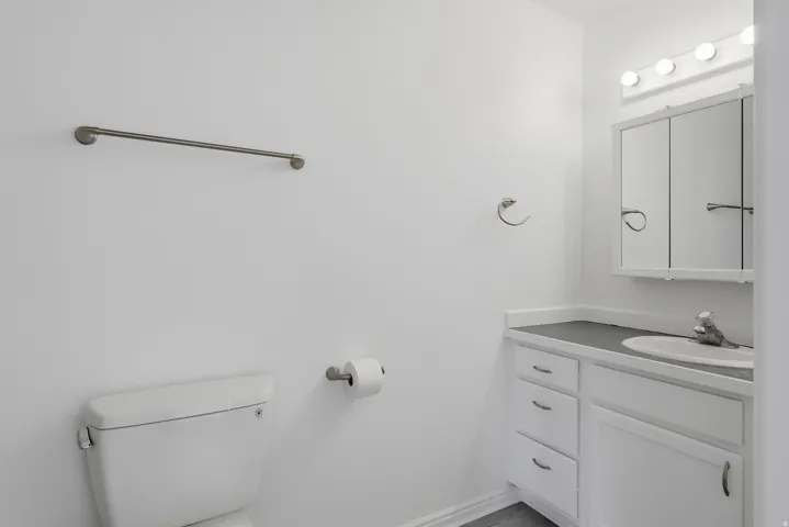 Bathroom vanity featuring a built-in sink, dark countertop, and white cabinetry