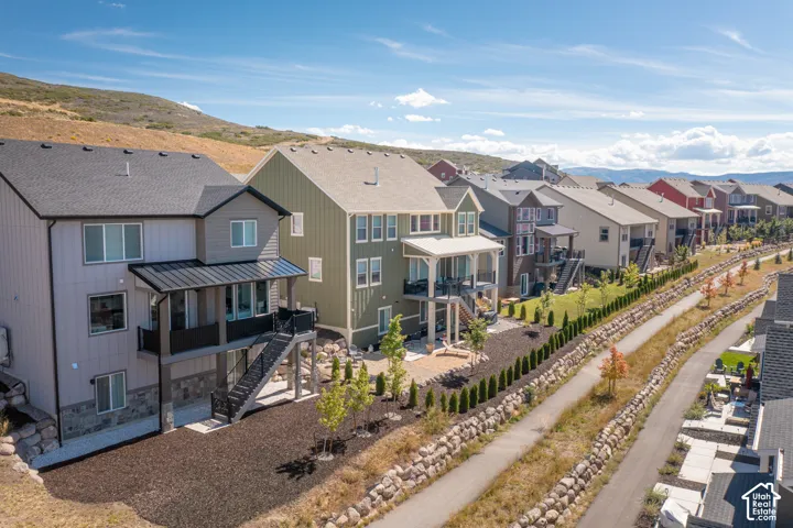 Multi-story residential exteriors featuring vertical siding, stone veneer accents, elevated covered decks with metal railings, and exterior staircases