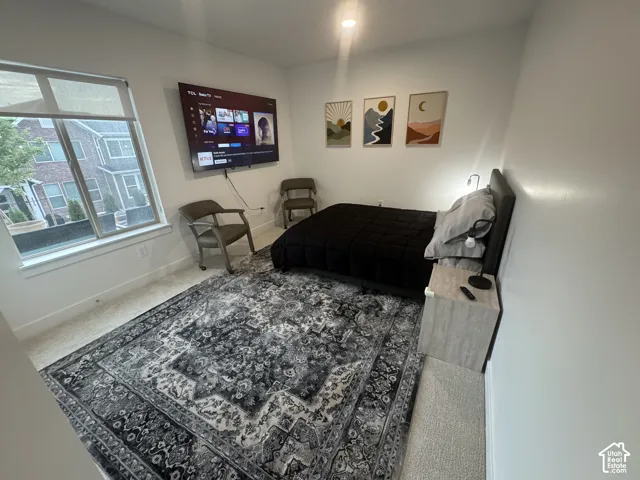 Recessed lighting illuminates this room, featuring carpeted flooring and white painted walls