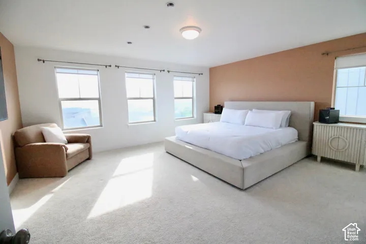 Spacious room featuring light-colored carpeting, three windows, recessed lighting, and a flush mount ceiling light