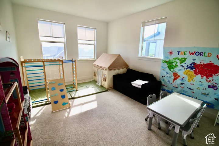 Bright room featuring three large windows with roller shades and plush carpet flooring