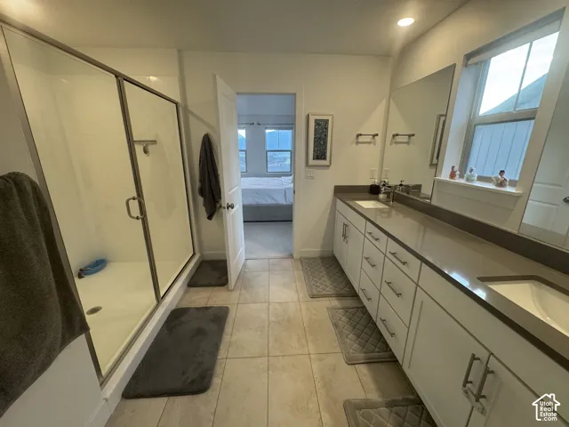 Spacious bathroom featuring a glass-enclosed shower, dual vanity with undermount sinks, and ample natural light from large windows
