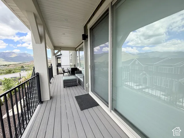 Expansive outdoor balcony featuring composite decking, a black metal railing, and an overhead soffit with recessed lighting