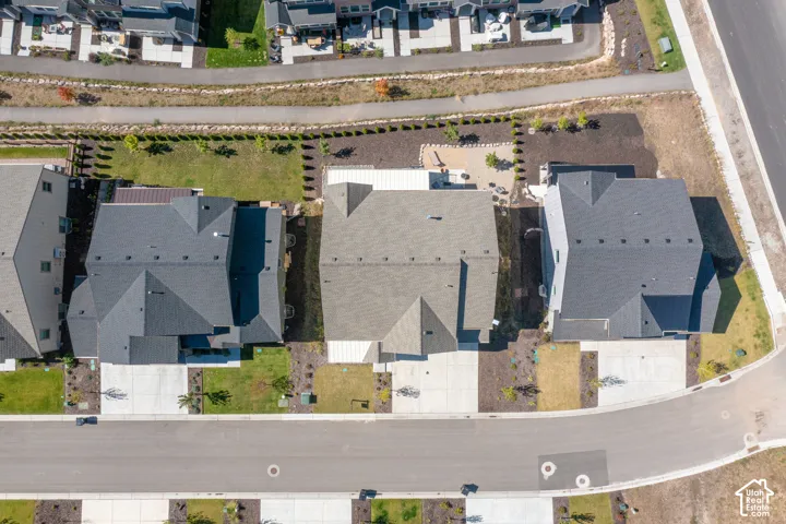 Aerial perspective featuring multi-story residences with asphalt shingle roofs, concrete driveways, and landscaped rear yards