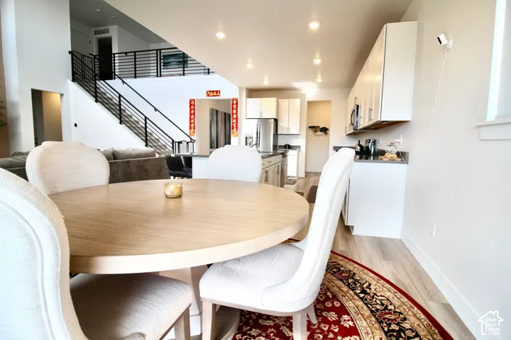 Open-concept living space featuring wood-finish flooring, recessed lighting, and a modern kitchen with white cabinetry and stainless steel appliances