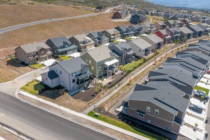 Aerial perspective of a multi-story residential community featuring asphalt-shingle roofing, concrete driveways, paved street infrastructure, and landscaped residential lots