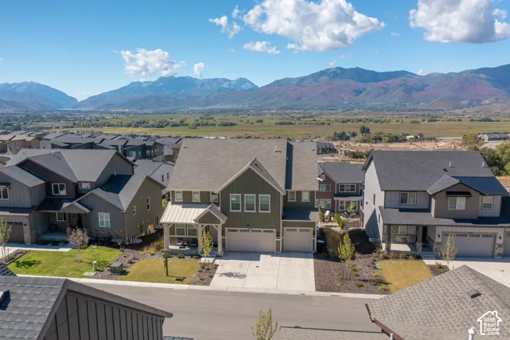 Two-story residence featuring a shingled roof, metal-accented front porch, multi-car garage, and mountain backdrop