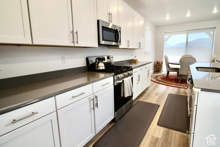 Modern kitchen featuring white shaker cabinetry, stainless steel appliances, and a gas range