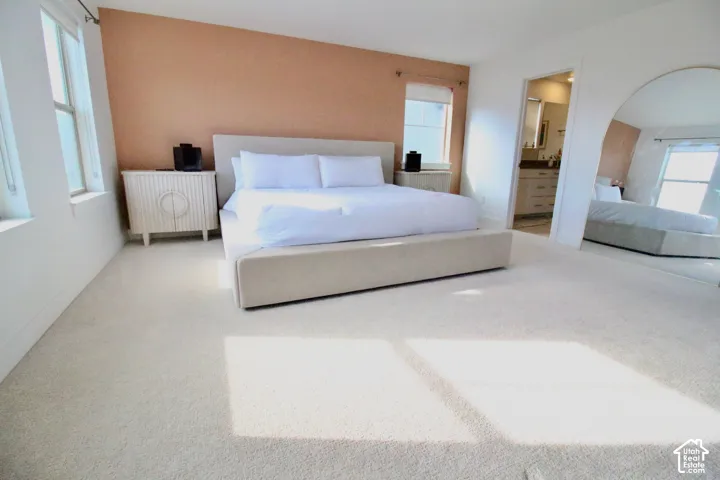 Carpeted interior space featuring multiple windows, a textured accent wall, and a built-in archway