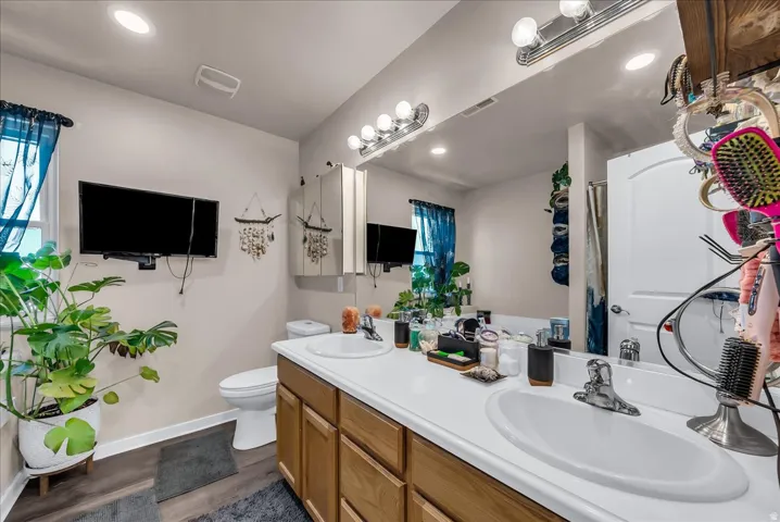 Dual vanity bathroom featuring white quartz countertops, wood-finish cabinetry, and brushed nickel fixtures