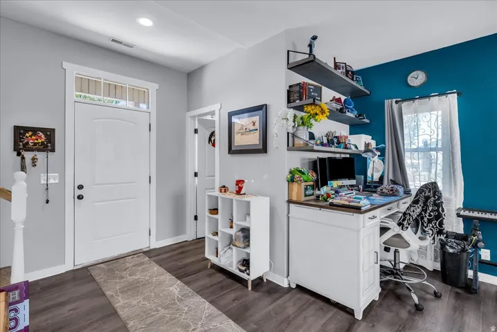 Wood-finish flooring, recessed lighting, built-in shelving, white paneled door with transom window, and a white built-in desk