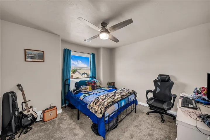 Neutrally painted walls with a textured ceiling, a window with blue curtains, and gray carpeted flooring