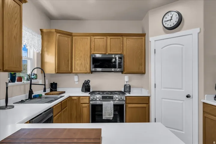 Galley-style kitchen featuring wood-finish cabinetry, white quartz countertops, stainless steel gas range with convection oven, and matching microwave
