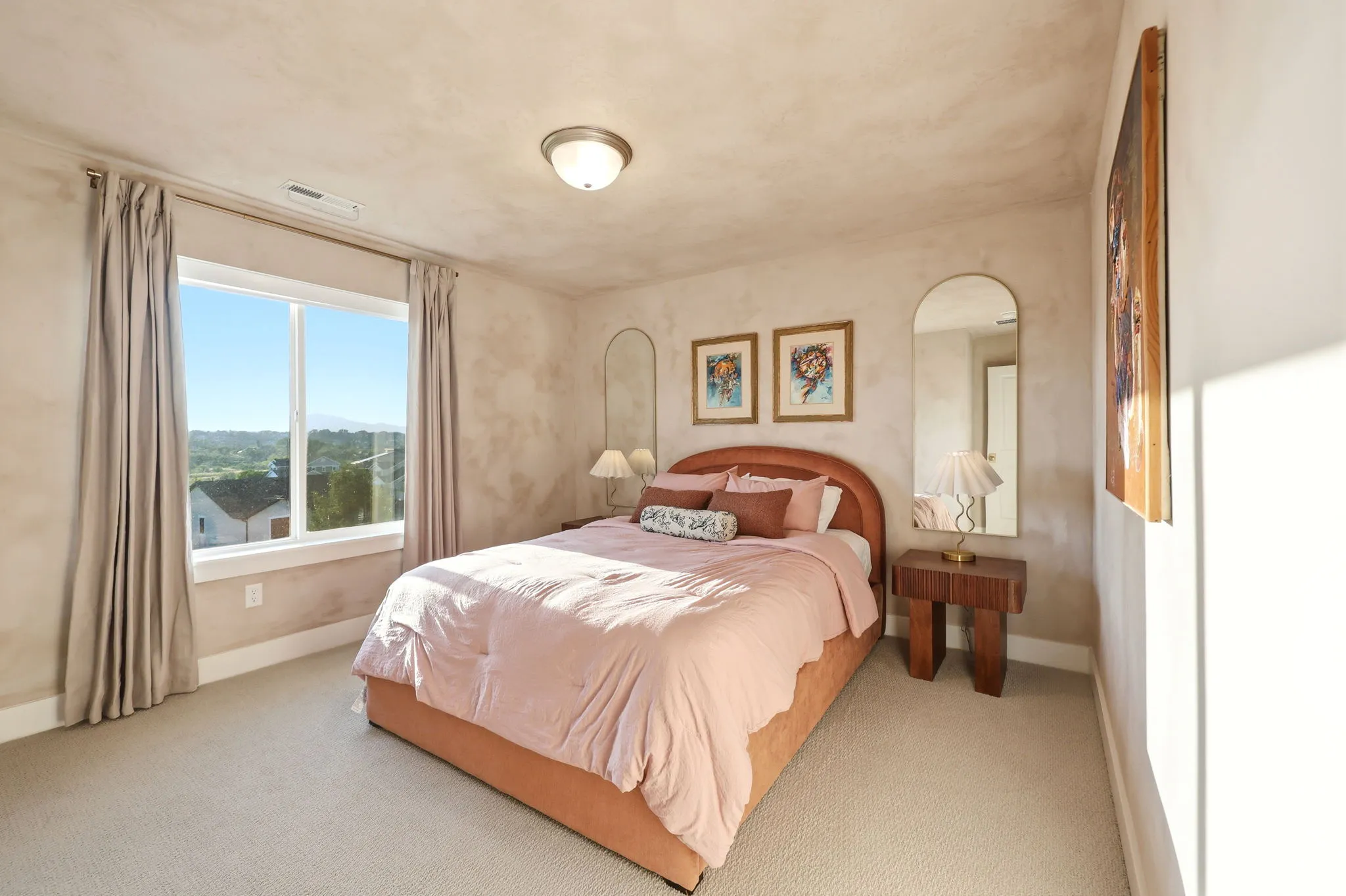 Spacious bedroom featuring a wood-finish upholstered bed frame, neutral carpet flooring, and large picture window with natural light