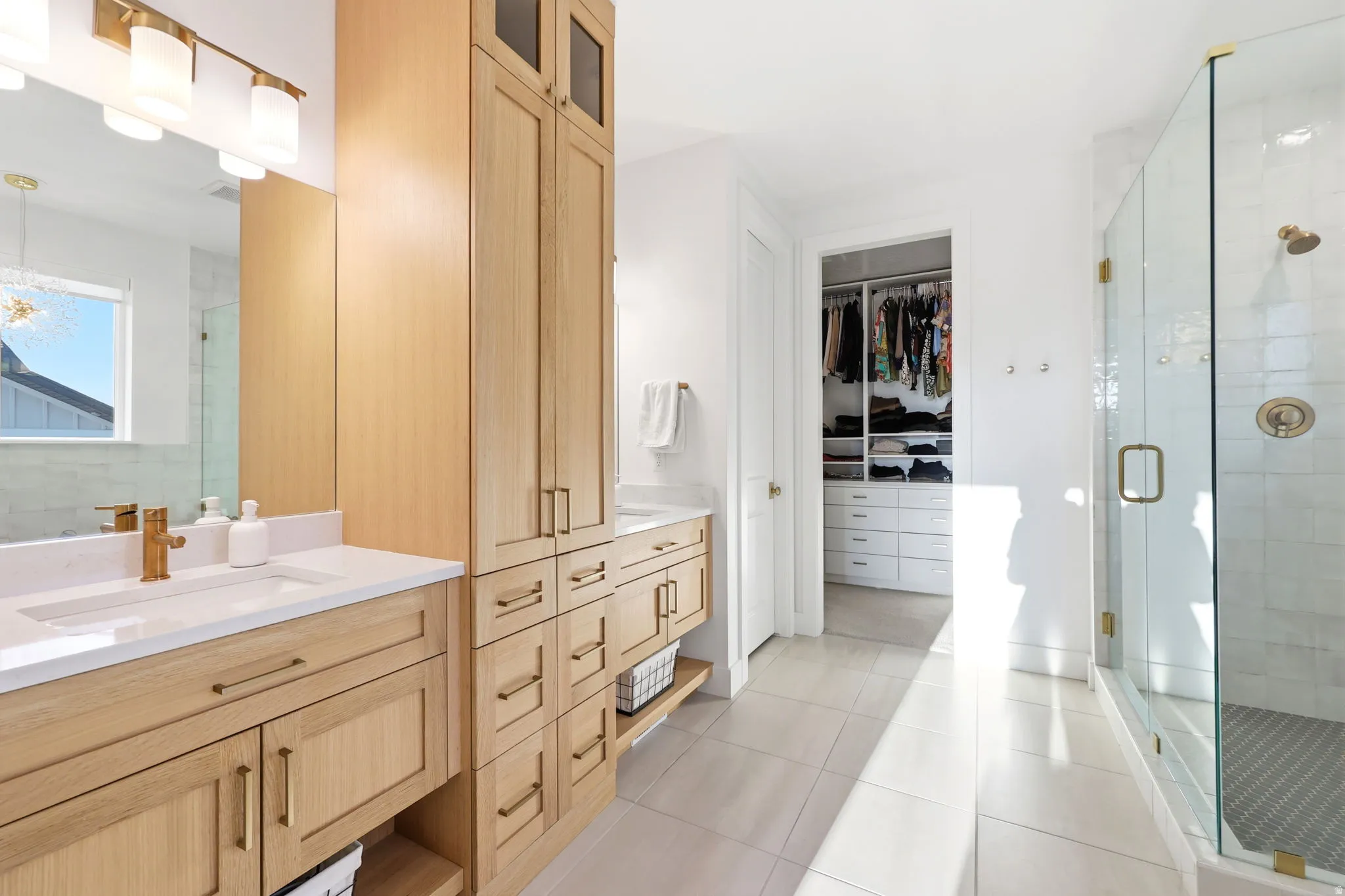 Primary Bathroom Suite featuring dual vanity with warm wood-finish cabinetry, white countertop, and integrated storage