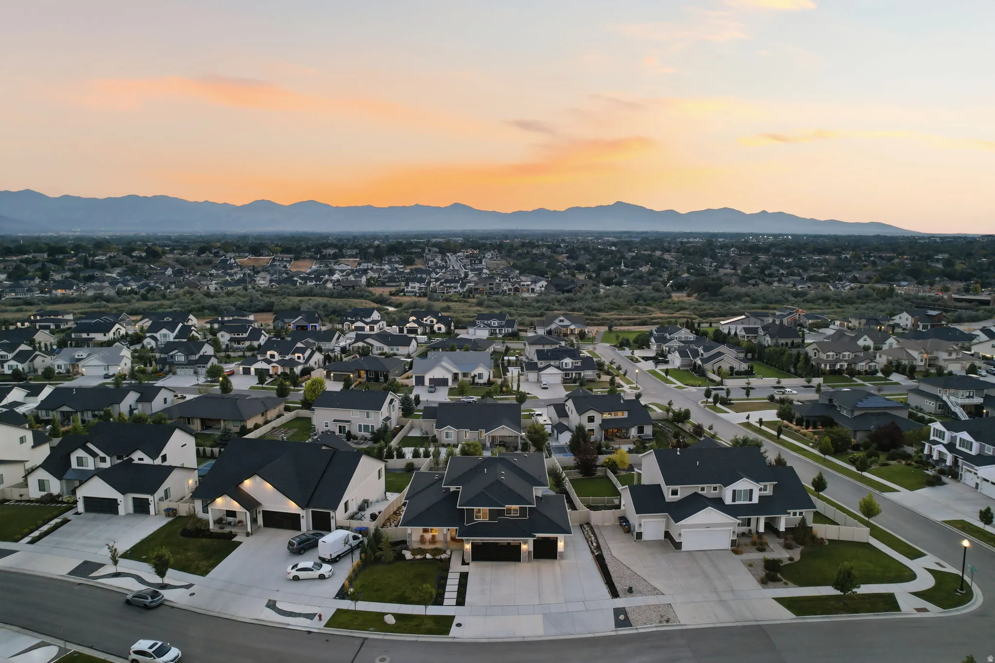 Elevated aerial perspective showcasing a refined residential community with meticulously landscaped properties, mature tree-lined streets, and custom architectural designs