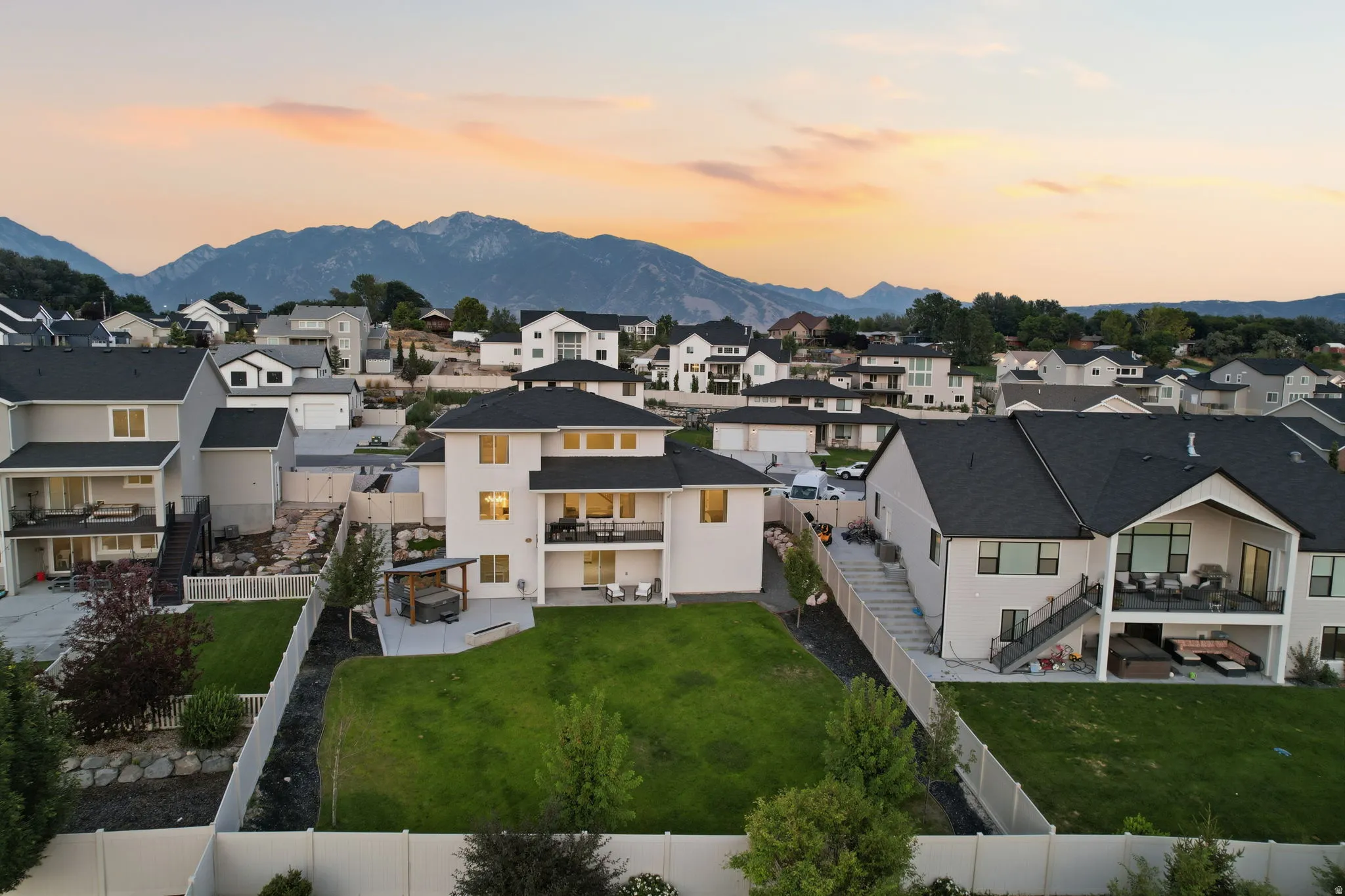 Expansive backyard retreat featuring a manicured lawn, mature landscaping, and white perimeter fencing