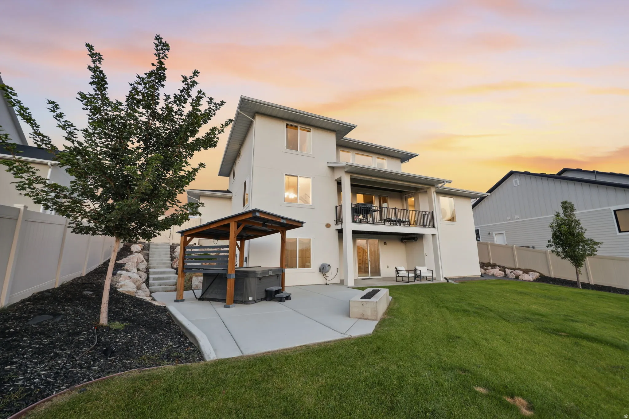 Modern two-story residence with clean-lined architecture featuring a light-colored exterior, multi-level deck design, and expansive rear yard with mature landscaping