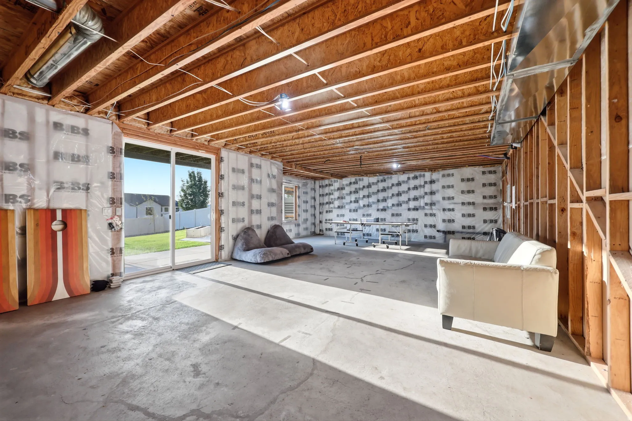 Spacious garage workshop featuring exposed wood-beam ceiling with skylights, concrete flooring, and large glass entry door with natural light
