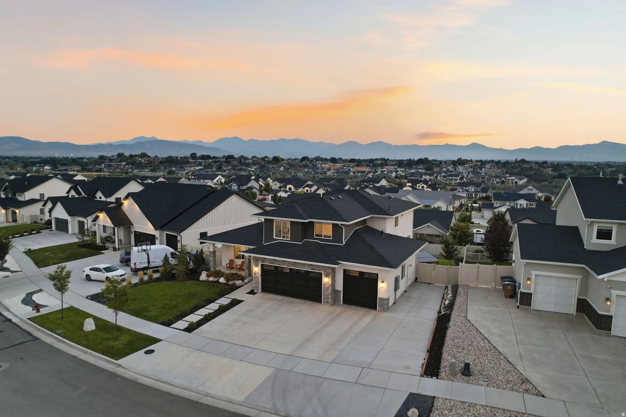 Modern residential estate showcasing a striking contemporary design with clean architectural lines, featuring a light-toned exterior complemented by dark roof accents and a two-car garage with stone detailing