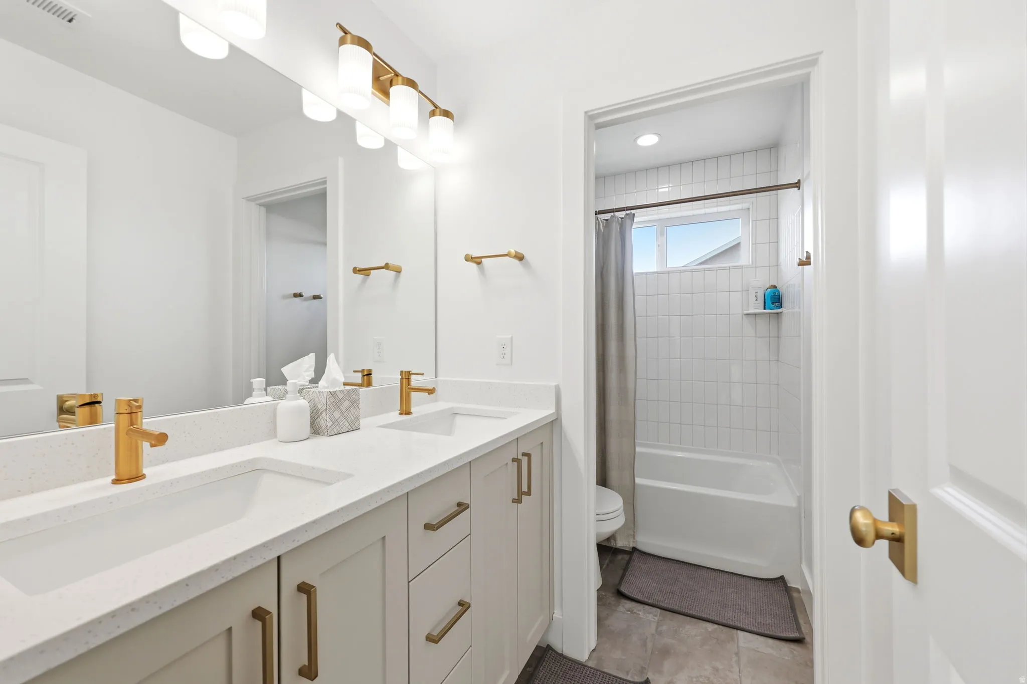 Spa-inspired primary bathroom featuring a dual-sink vanity with soft-close cabinetry, white quartz countertop, and brushed gold hardware