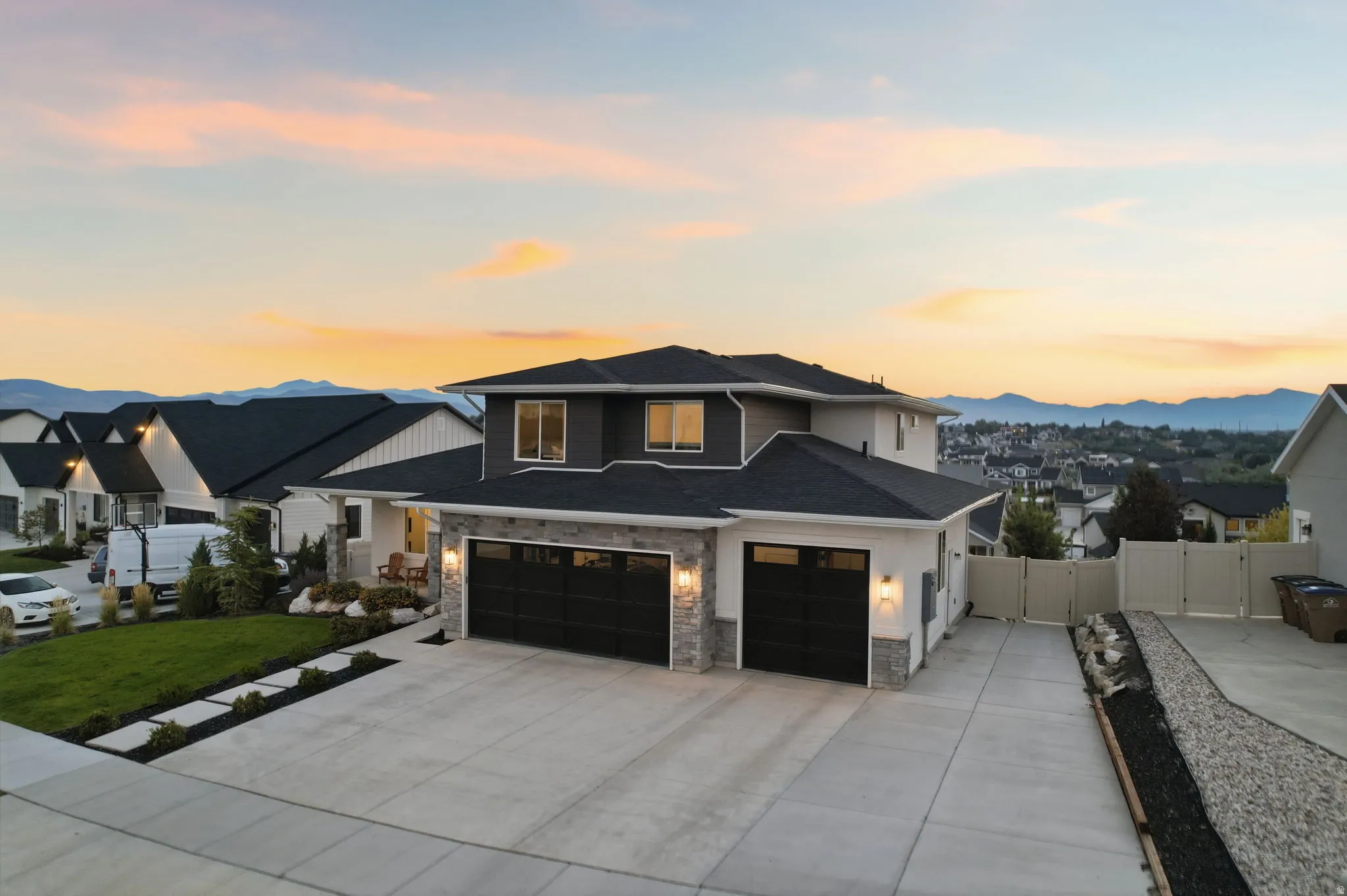 Contemporary two-story residence featuring a dark gray and white exterior with stone accents