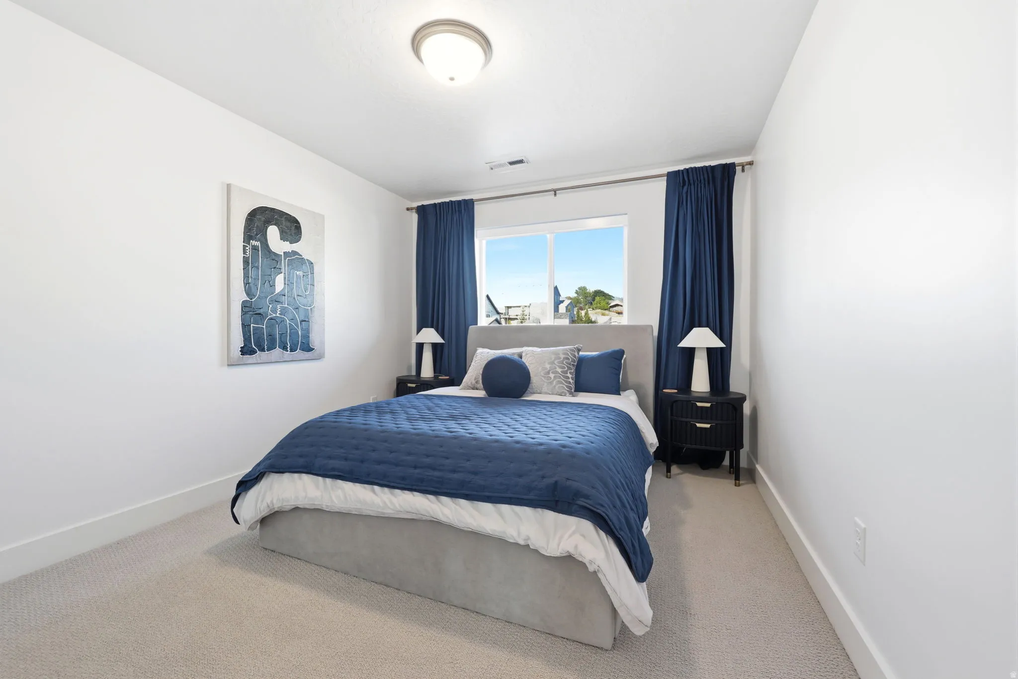 Bright room featuring a window with dark blue drapes, light-colored carpeting, a contemporary ceiling light fixture, and white wall finishes