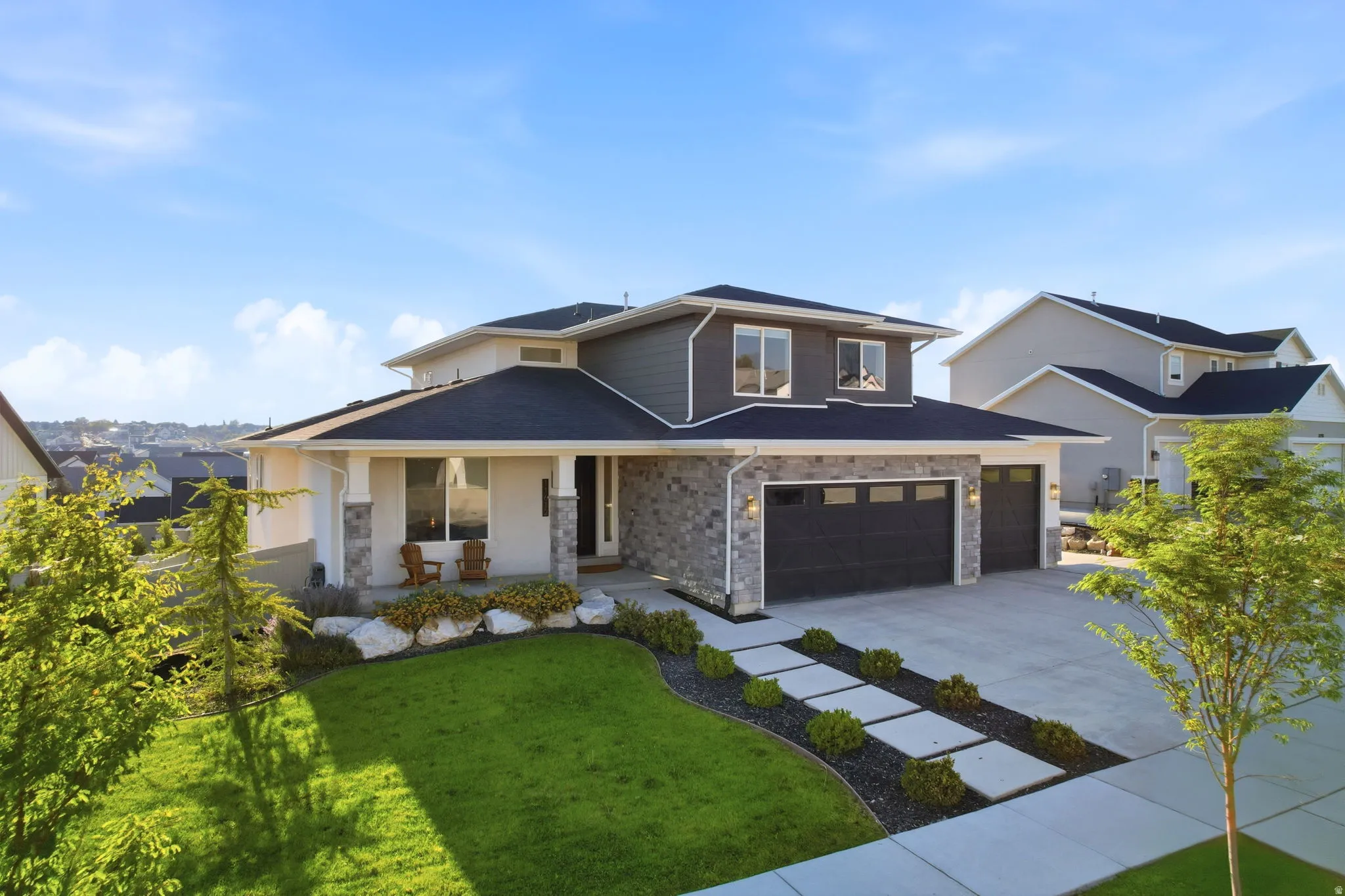 Modern two-story residence featuring a cream and charcoal exterior with mixed stone and siding finishes