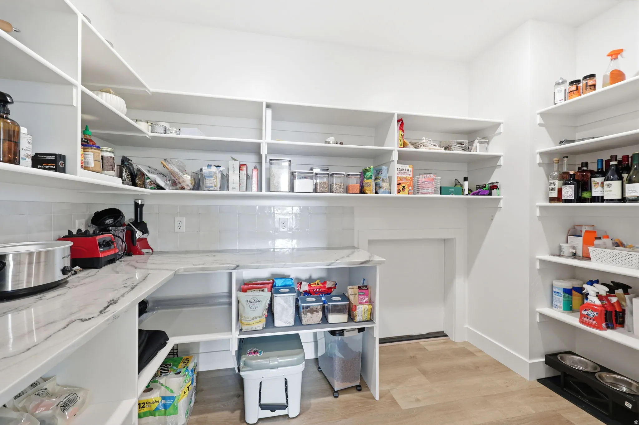 Spacious pantry with extensive built-in shelving, durable wood-finish flooring, and a marble-look countertop