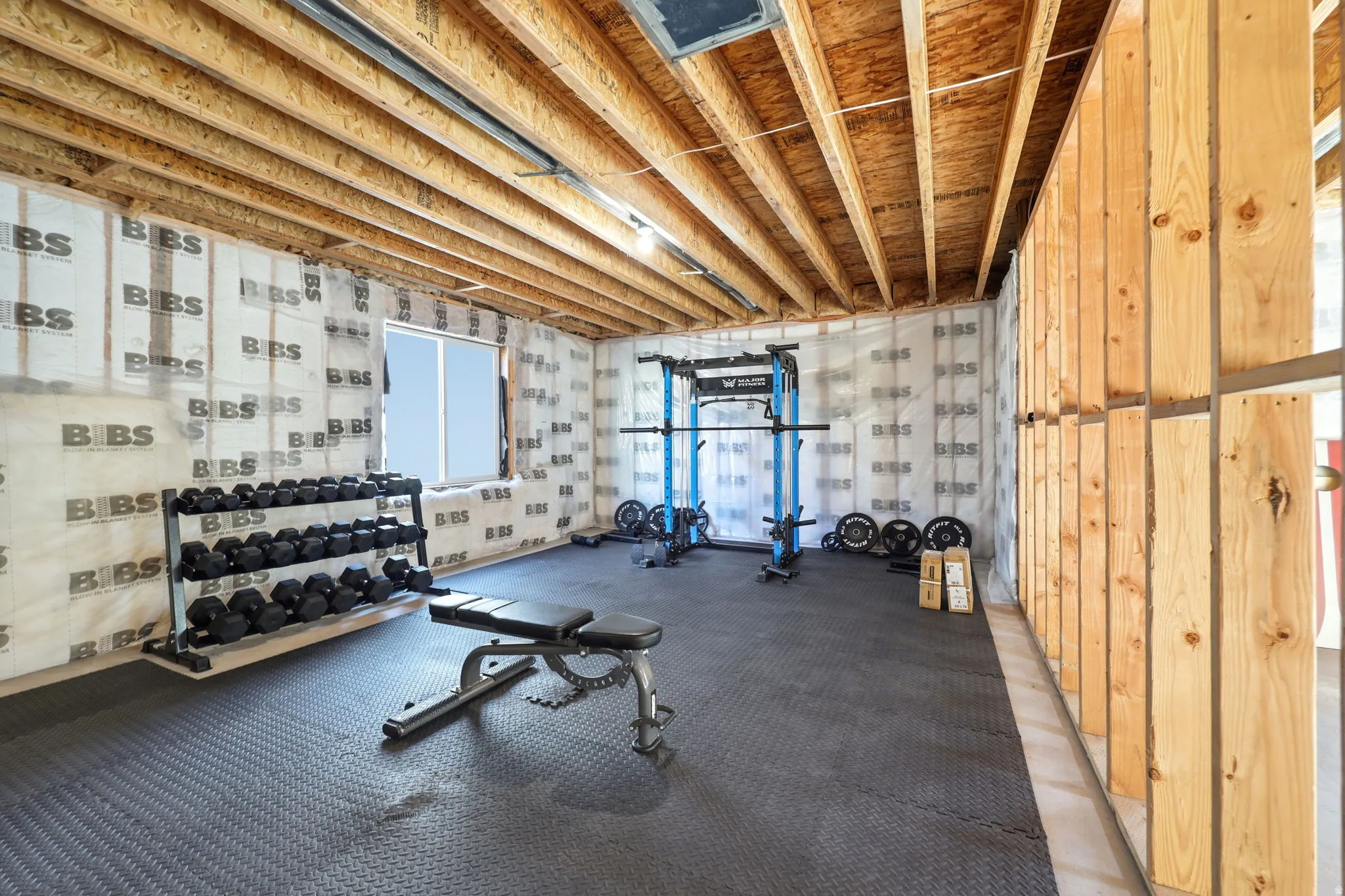 Dedicated fitness studio featuring exposed wood beam ceiling, rubber flooring, and comprehensive equipment storage